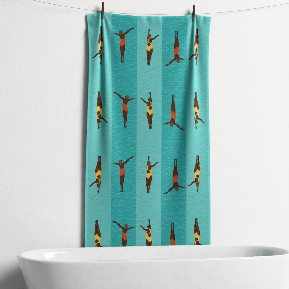 A custom swim towel pegged to a suspended line above a white bath. The towel features a repeat pattern of two black women swimmers in bright swim costumes