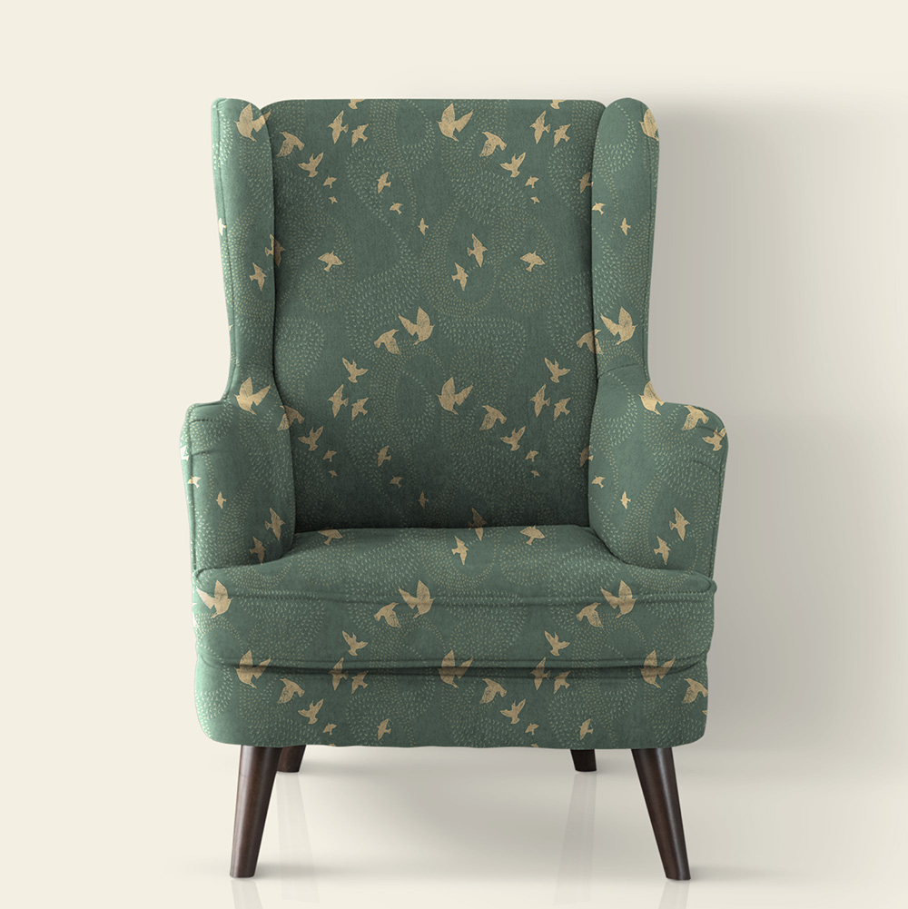 A high back arm chair against a white background. Upholstered in a blue fabric featuring murmurations in swirls with close ups of white birds.