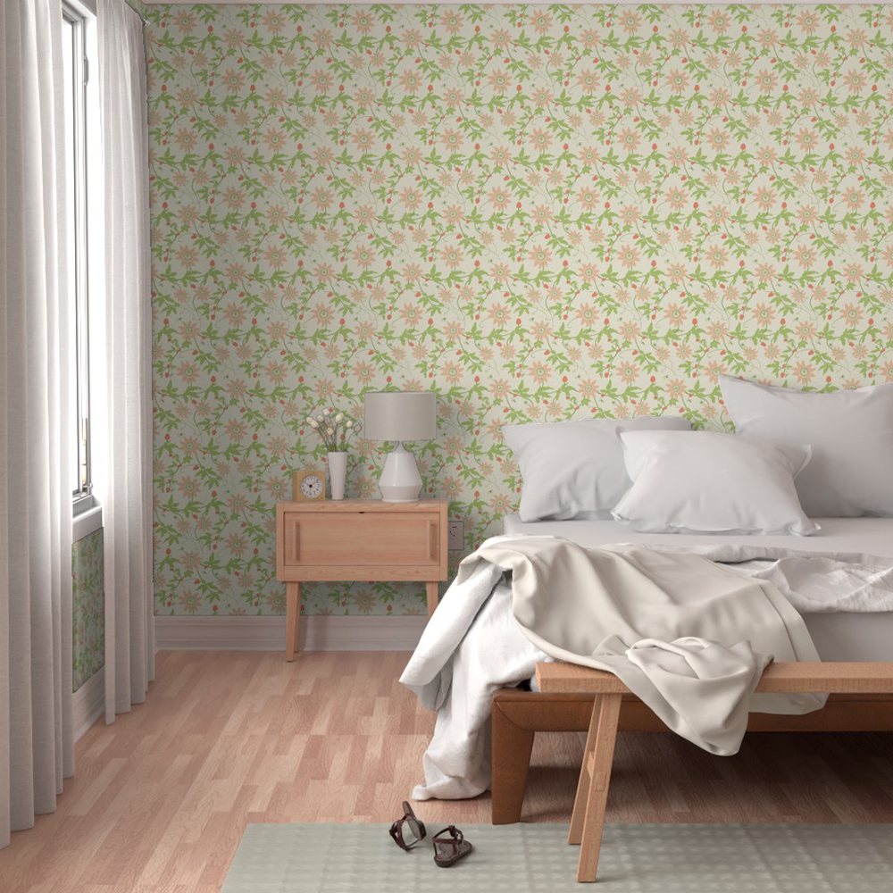A bedroom scene showing part of an unmade double bed with white linen, lit by a side window with white drapes. Next to the bed is a beside table with a white lamp, a white vase with white flowers and a wooden clock. The wallpaper is a repeat pattern of green leaves with pink Passiflora flowers and buds on a cream background.