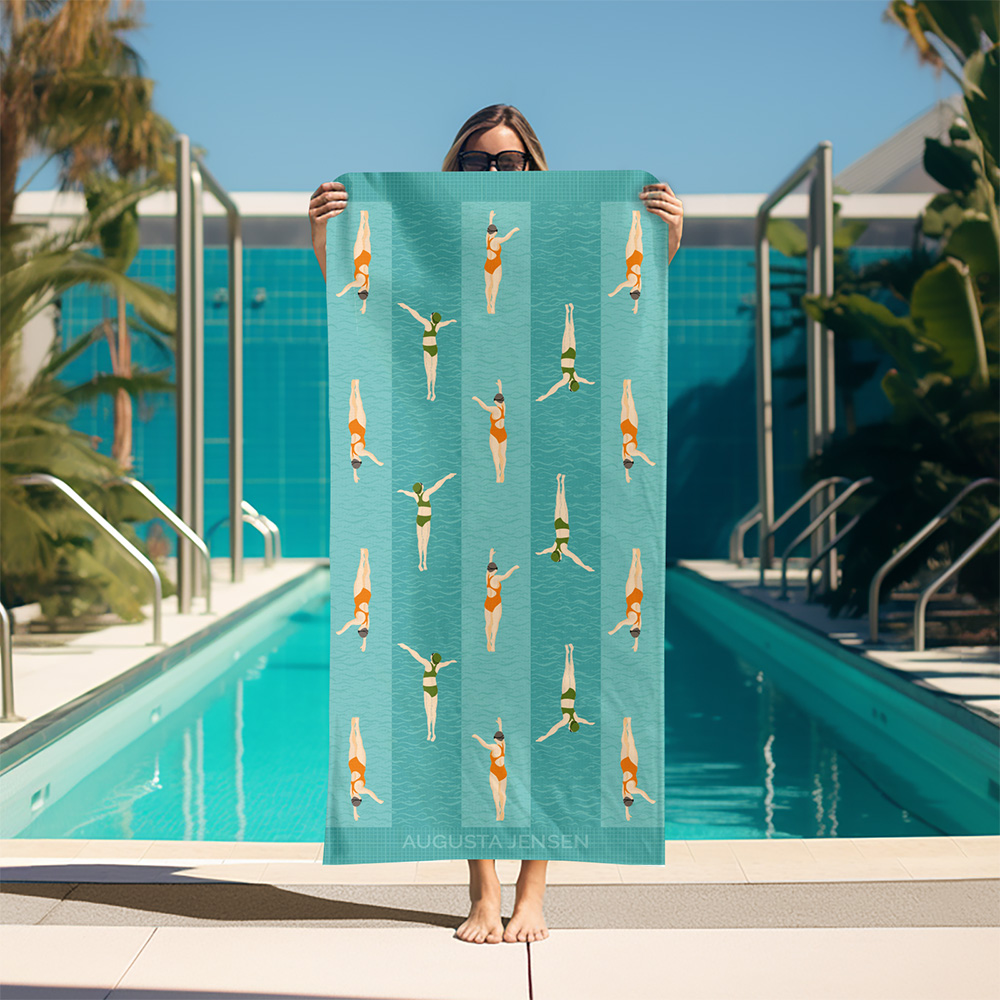 A woman holding up a custom swim towel in front of a outside pool surrounded by tropical plants. The towel is a custom towel and features a striped pattern of two white women swimmers.