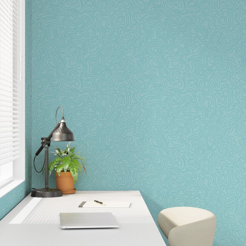 A study room scene showing a white desk and chair side on, in front of a window with white blinds. On the desk in a potted plant, a metal lamp and a closed laptop. The wallpaper is a blue repeat pattern of abstract water swirls