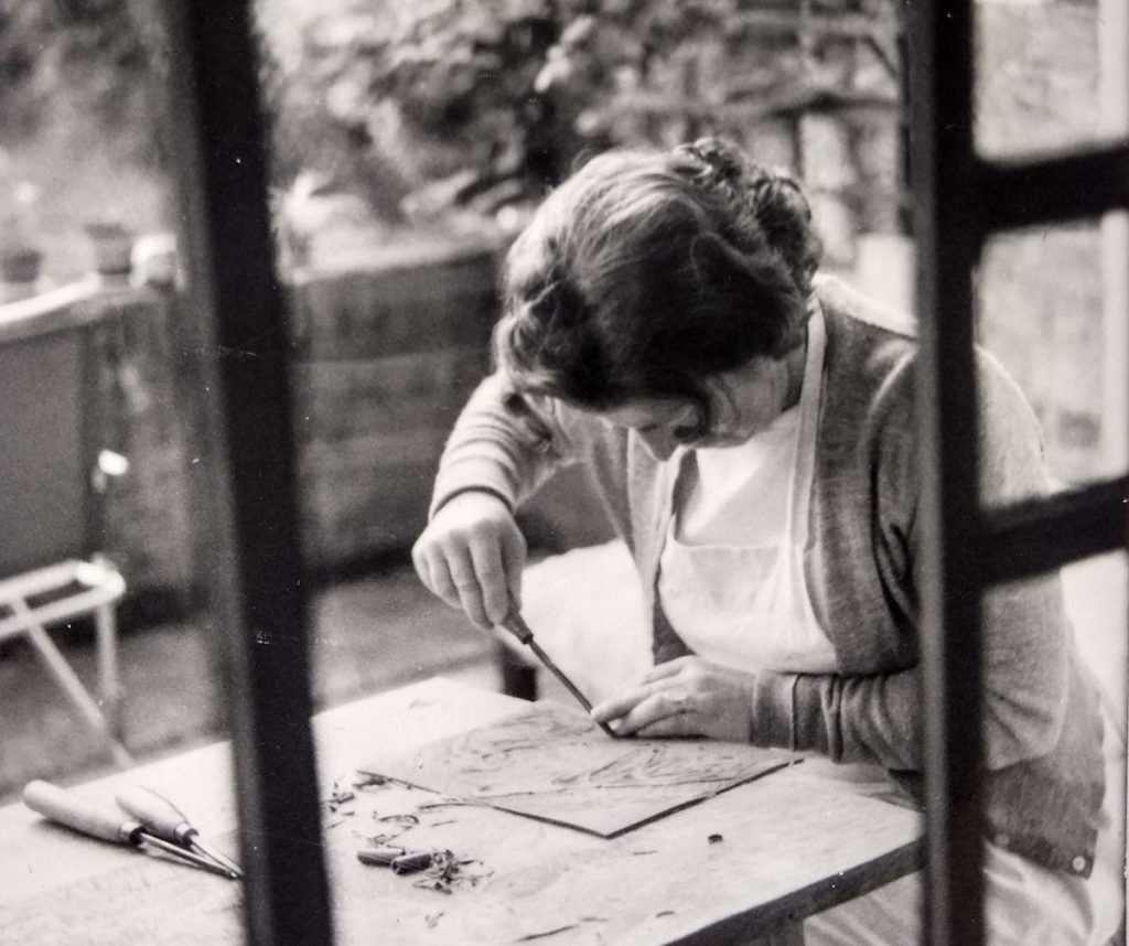 Black and white photo of Ulla Frisch working on a linocut